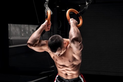 Athlete does warm-up on gymnastic rings. The concept of sport and healthy lifestyle.