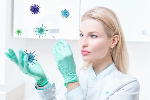 Portrait of a blonde girl in a medical gown with a syringe in her hands. Covid vaccine concept. Epidemic