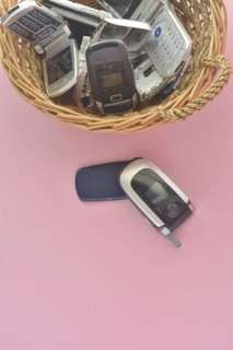 An assortment of vintage mobile phones in a basket with one flip phone placed in front