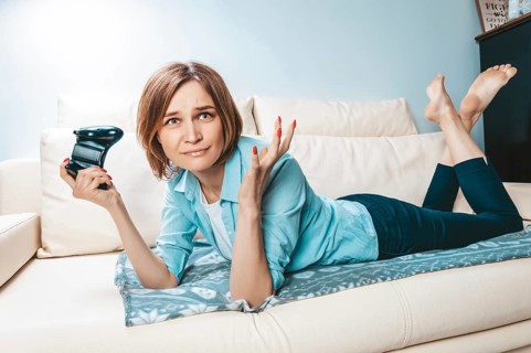 Girl with a joystick in her hands lies on the couch and plays a computer game. ESports concept.