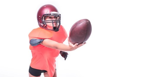 Woman in the uniform of an American football team player throws the ball. Sports concept.