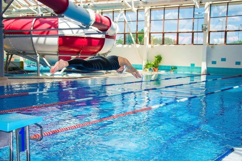 Professional athlete jumps into the water in the pool from the platform