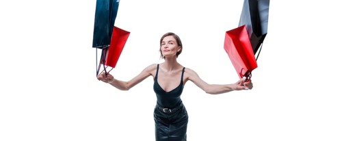 Cheerful positive girl jumps up with happiness and waving shopping bags. The concept of holiday gifts
