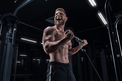 Portrait of an athlete pumping biceps in a crossover. Bodybuilding and fitness concept.