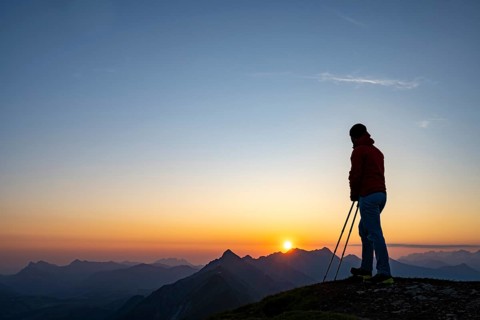 Mountaineer on mountain ridge with Rothorn peak in the background at sunrise