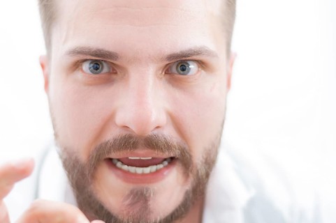 Stylish man with a crazy look is looking at the camera. The concept of suppression