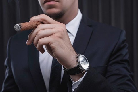 Portrait of a stylish man in a suit with a cigar. Business concept.