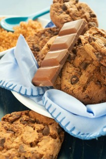 Close-up of chocolate chip cookies and a chocolate bar on a blue napkin