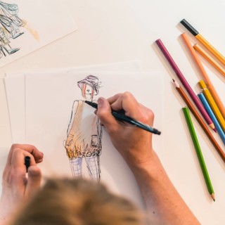Top view of a fashion designer drawing a fashion sketch