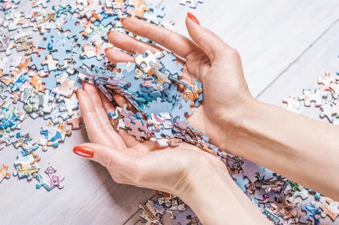 Woman holds a pile of puzzles in her hands. The concept of board educational games. Stay at home.