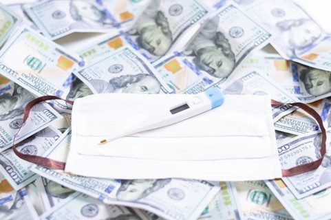 Medical mask and a thermometer lie on one hundred dollar bills. The concept of an epidemic