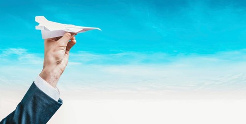 Image of a hand holding a paper airplane. Tourism concept.