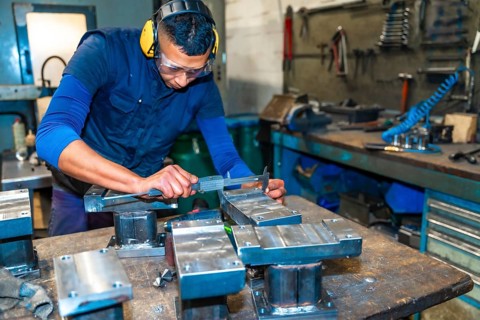 A Latin operator making measurements with the caliper on a milling cutter in a numerical control workshop