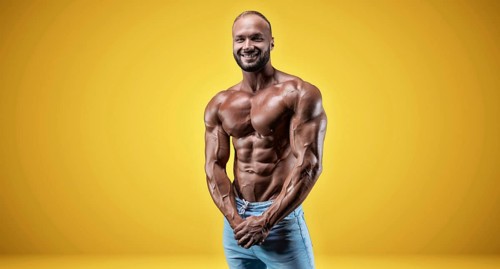 Isolated professional sportsman on a yellow background. Bodybuilding concept. Panorama. Advertising of a gym and sports nutrition.