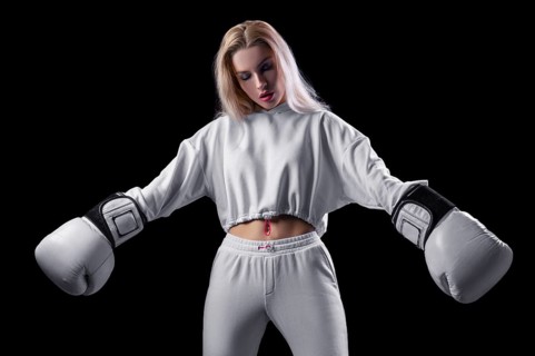 Charming girl in a white sweatshirt posing with huge white gloves. The concept of sports