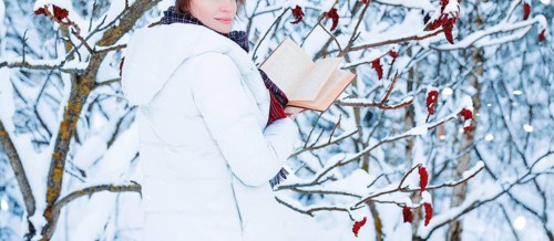 No name portrait of a charming girl who reads a book in the winter forest. Concept of Christmas