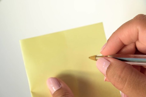 Woman's hand with painted nails holding blank letter paper on pure white background