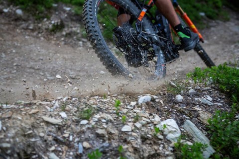 A mountain bike tyre that drifts and throws gravel into the air on the trail