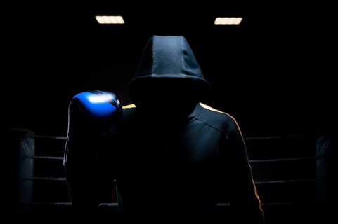 World champion in Thai boxing stands in the background of the ring with a raised blue glove. The concept of sport