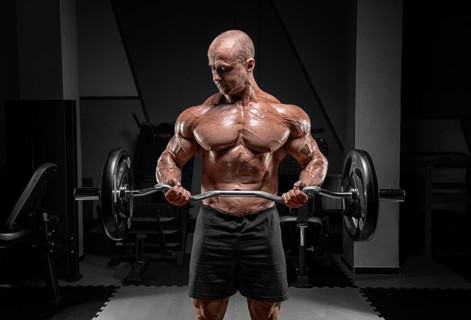 Professional weightlifter posing in the gym with a barbell in his hands. Classic bodybuilding.