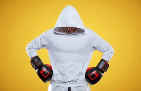 Male trainer posing in the studio with boxing gloves. White hoodie. Mixed martial arts concept. High image quality