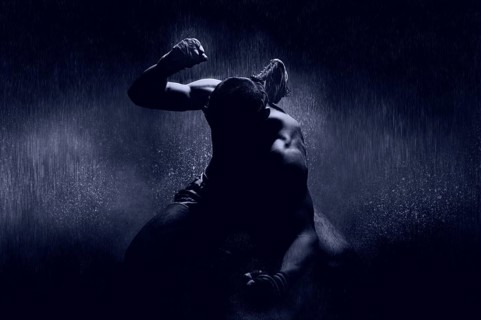 Thai boxer in the rain and under a blue spotlight. Mongkhon. The concept of victory in competitions