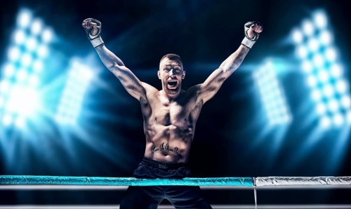Kickboxer posing in the ring. The athlete climbed the ropes and took a victorious position against the background of spotlights. The concept of mma