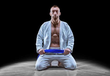 Professional athlete sits in the gym in a kimono with a blue belt. Concept of karate