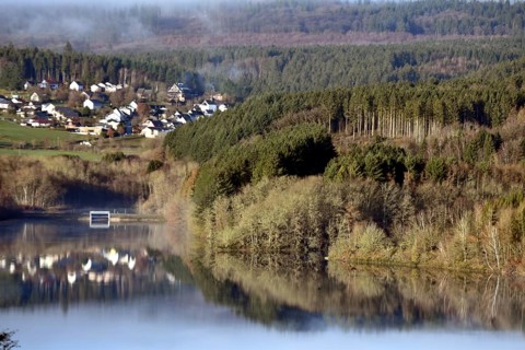 The Steinbach Dam near the national park community of Langweiler on the edge of the Hunsrueck-Hochwald National Park with fog on an early winter morning