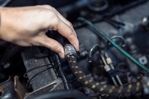 Auto mechanic regulates fuel supply with throttle cable lever