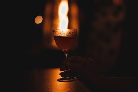 Image of a glass with a cocktail in a night bar against the background of a fiery heater. Restaurant concept
