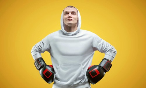 Male trainer posing in the studio with boxing gloves. White hoodie. Mixed martial arts concept. High image quality