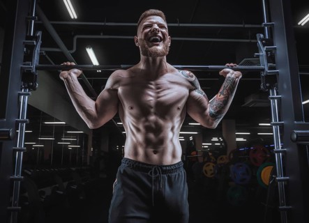 Portrait of an athlete with a barbell on the shoulders of the gym. Bodybuilding and fitness concept.