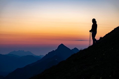 Mountaineer on mountain ridge with Rothorn peak in the background at blue hour