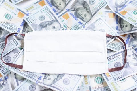 Medical mask rests on one hundred dollar bills. The concept of an epidemic