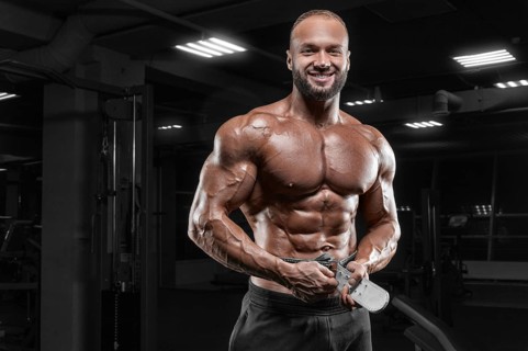 The athlete poses in the gym with an athletic belt. Fitness