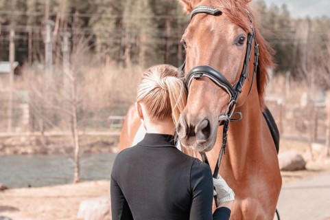 Beautiful stylish woman walking with a horse in a country club. Equestrian sport