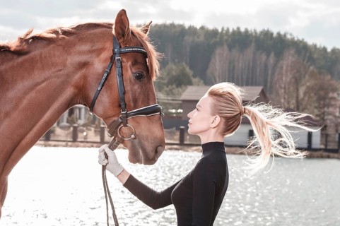 Beautiful stylish woman walking with a horse in a country club. Equestrian sport