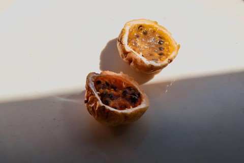 Juicy cut halves of a passion fruit with visible seeds in the sunlight