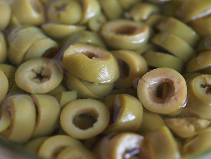 Sliced green olives in brine background