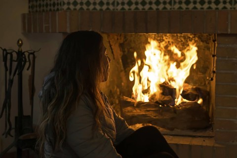 Latin woman sitting in front of the fireplace in the cold winters