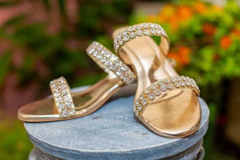 Gold-colored high heels with shiny rhinestones on a display stand