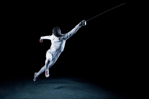 The fencer moves forward with a sword in his hand. Sport concept.