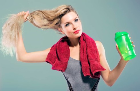 Charming model posing in the studio with a shaker in her hands and a towel around her neck.