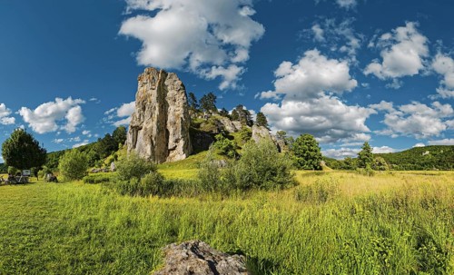 Striking limestone rock formation Burgstein with blue and white sky in the upper Altmuehltal surrounded by green vegetation