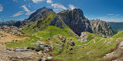 Panoramic view of a vast mountain landscape with green hills and blue sky