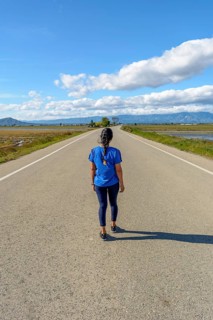 View from behind an individual walking along a deserted road with scenic views on a clear day