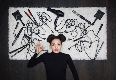 Young and charming girl with dreadlocks on her head shows an OK sign. The girl is lying on a white carpet. Around the tools for creating a