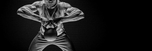 Portrait of an athlete pulling a kettlebell to his chin. The concept of sport and healthy lifestyle.