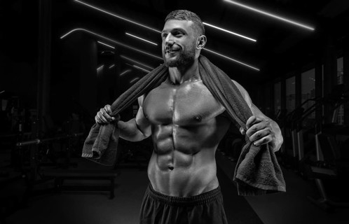 Muscular man posing in the gym with a towel on his shoulders. Fitness concept.